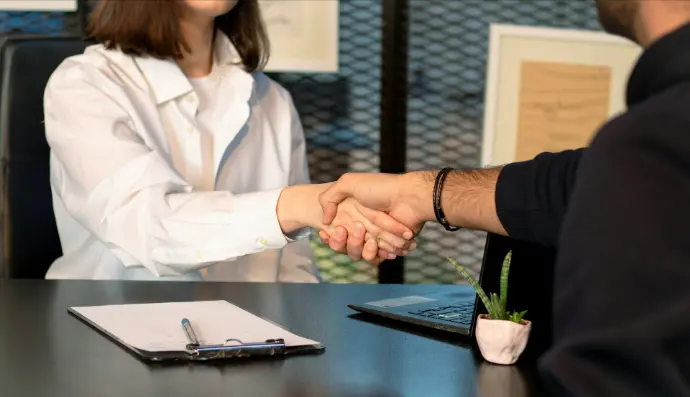 a man and a woman shaking hands in front of a laptop